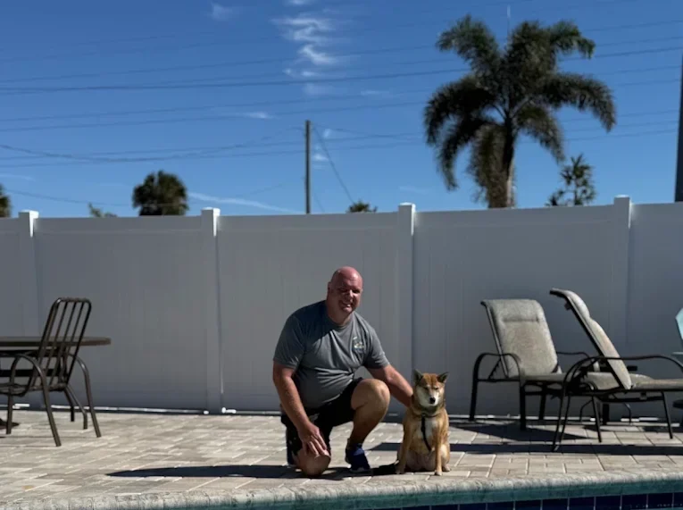 Pool owner relaxing with dog on pool deck